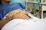 Anonymous woman lies in a bed with heart rate monitor clipped on finger at the Marie Stopes clinic in Melbourne.