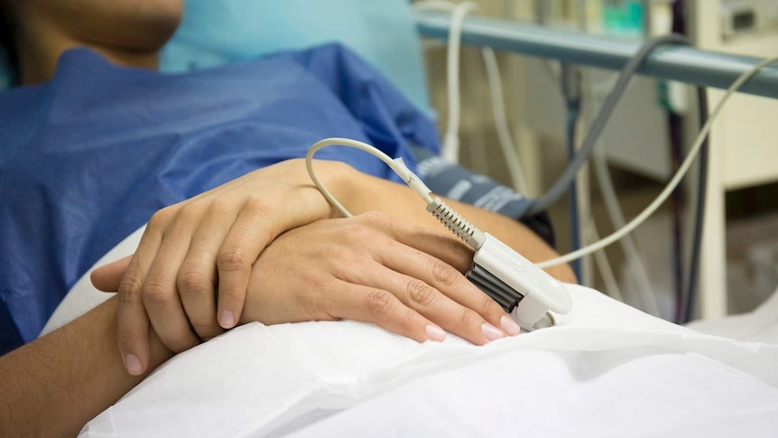 Anonymous woman lies in a bed with heart rate monitor clipped on finger at the Marie Stopes clinic in Melbourne.