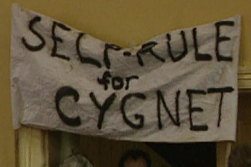 A grainy image of a hand-painted fabric sign that says 'self rule for Cygnet'