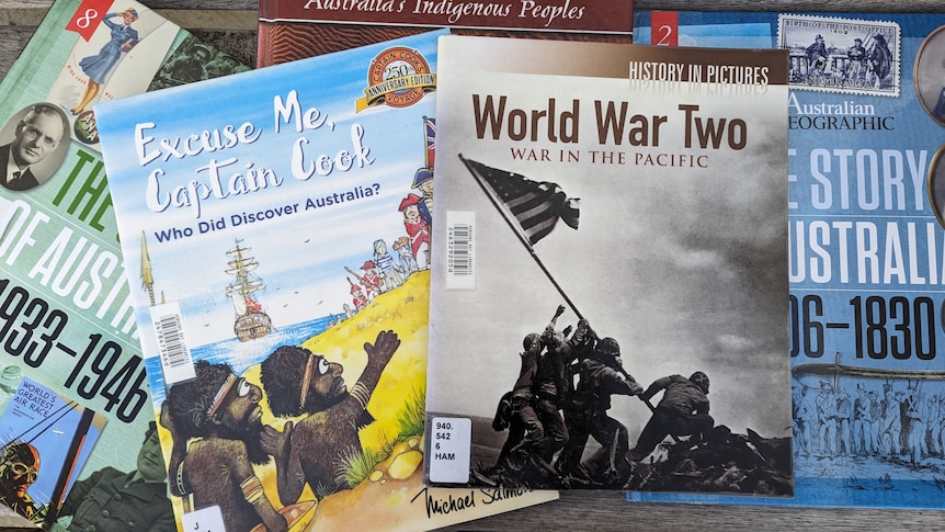 Various history books are seen on a tabletop. One is about World War Two and another Indigenous Australians and Captain Cook.