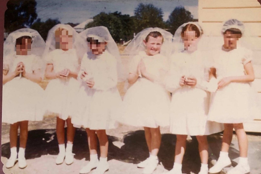 Five young girls dressed in white stand in a row