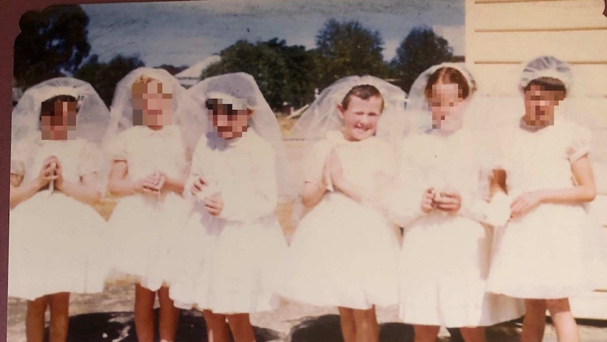 Five young girls dressed in white stand in a row