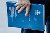 Jim Chalmers holds a copy of the 2024-25 budget outside of Parliament House