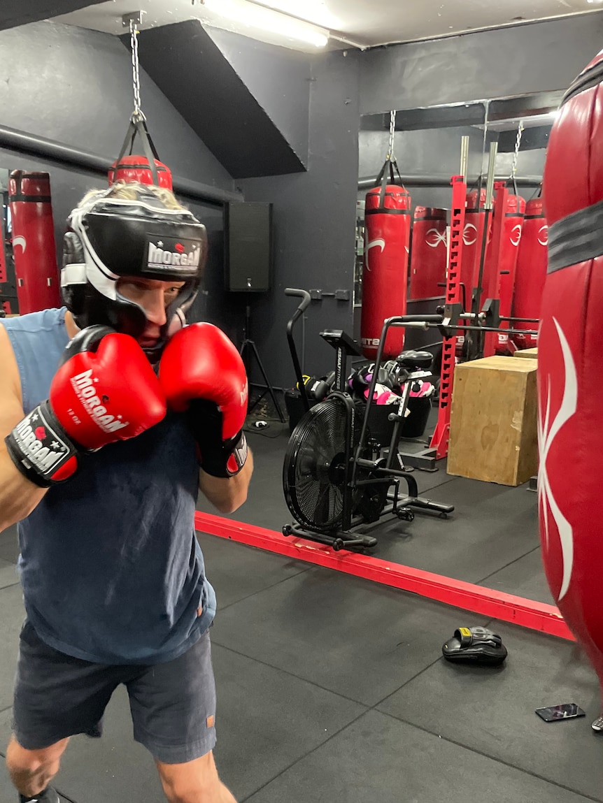 Boxer avec casque et gants devant un sac de boxe.