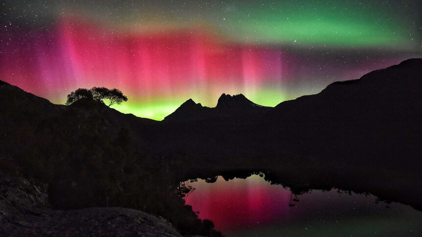 Cradle Mountain in Tasmania is silhouetted by an Aurora Australis.