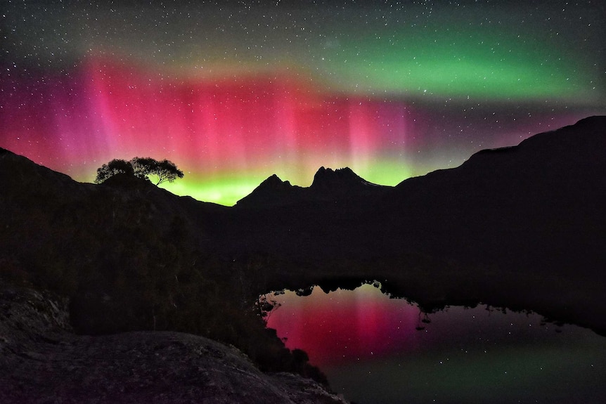 Cradle Mountain in Tasmania is silhouetted by an Aurora Australis.