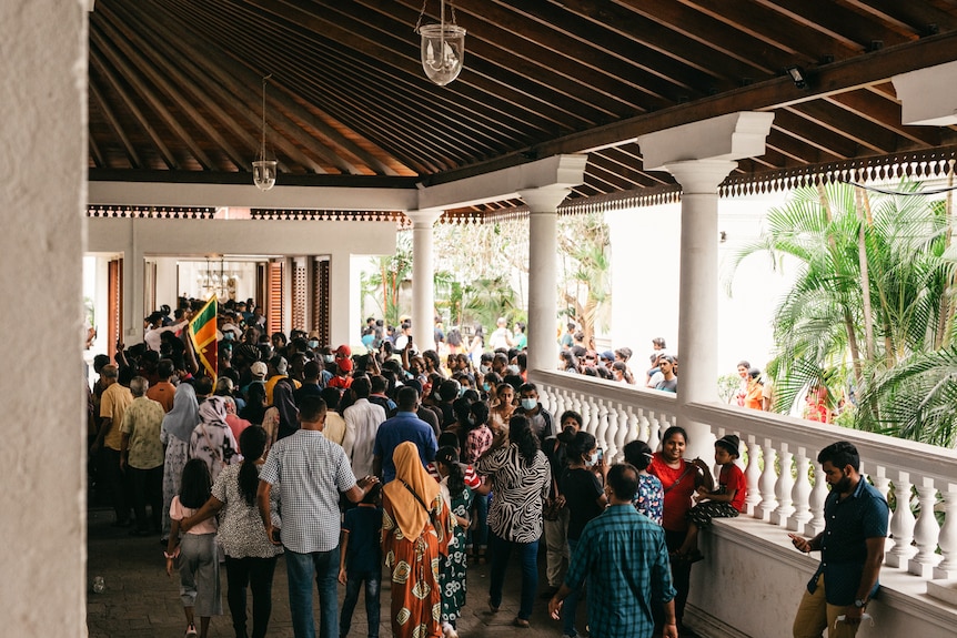 A group of people gathered on a balcony in a place holding signs and talking.