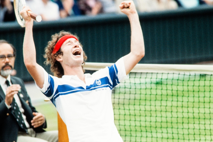 John McEnroe holds his arms up and sinks to his knees in celebration
