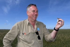 A man in a paddock holding a mouse.