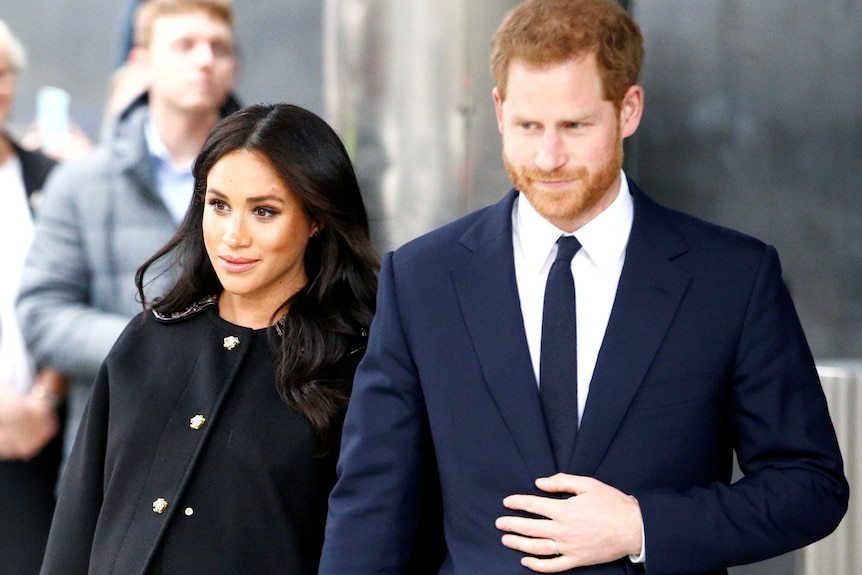 An attractive young couple dressed formally in suits.