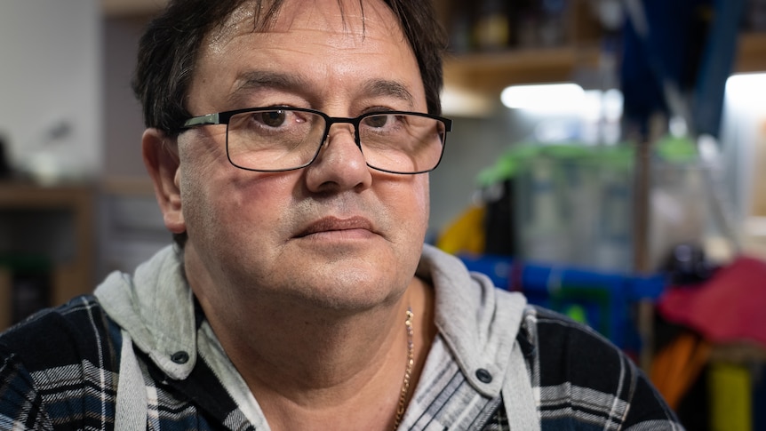 Man with glasses wearing a grey hoodie.