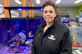 Woman stands in front of a fish tank inside a pet shop.