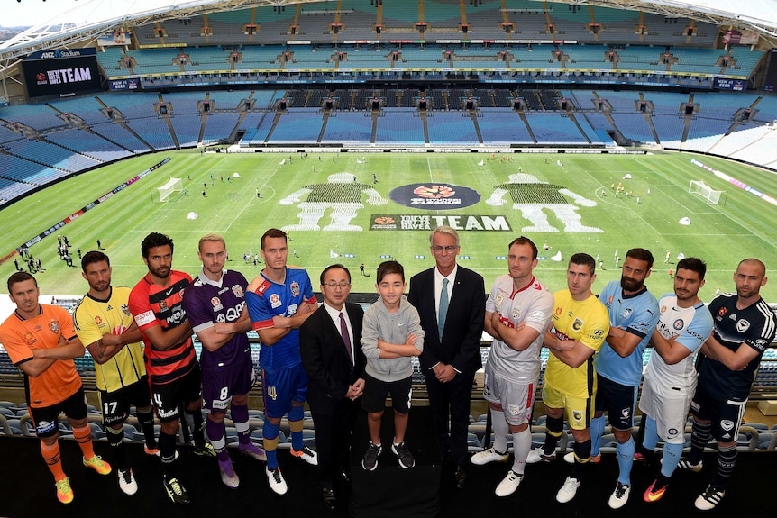 The captains of the A-League clubs pose in a line with a young boy and two men in suits.
