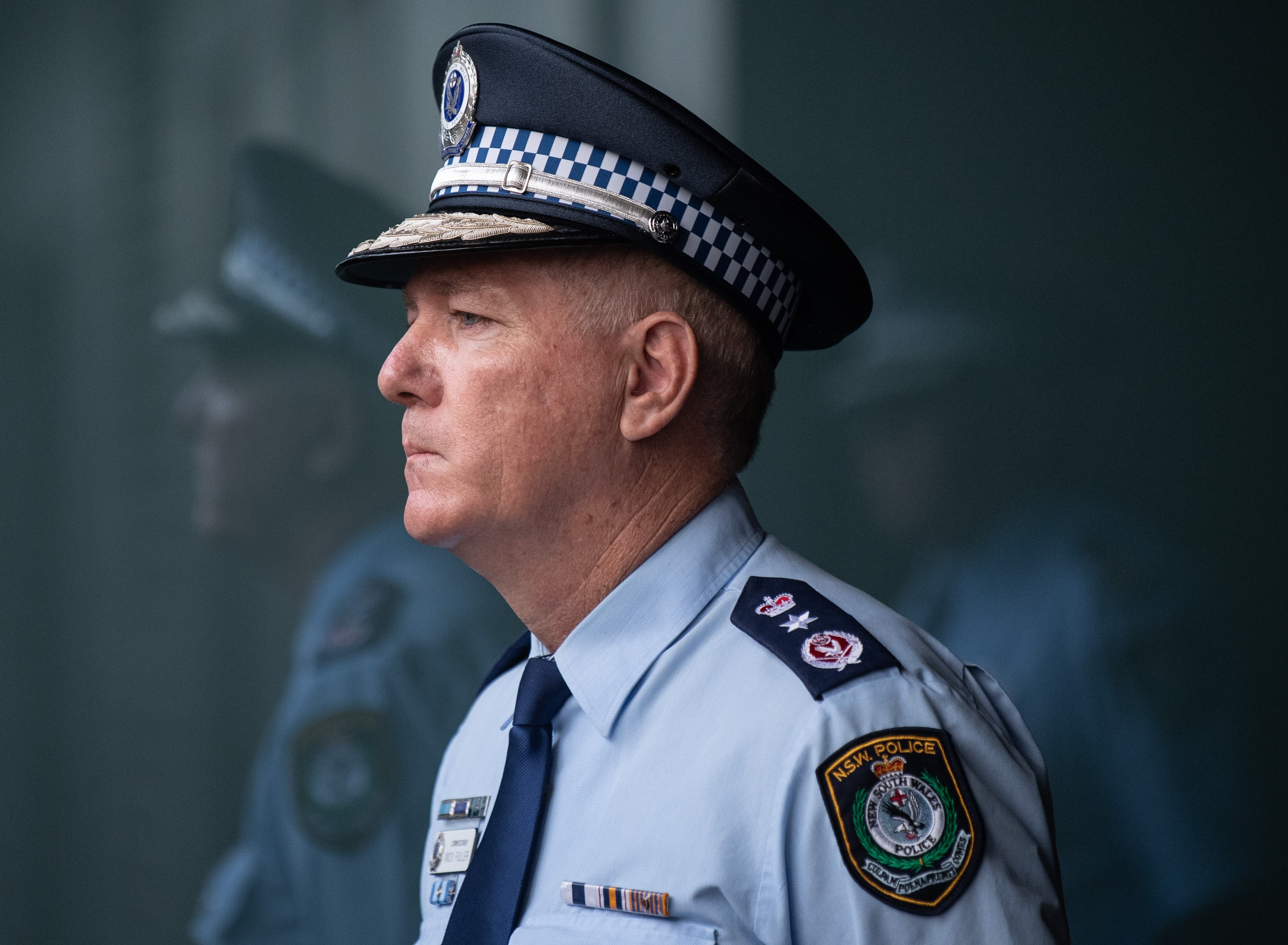 police commissioner mick fuller looking stern next to a reflection