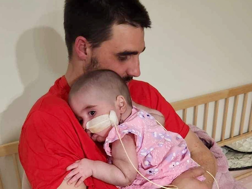 Aaron Ahern sostiene a su hija pequeña en el hospital