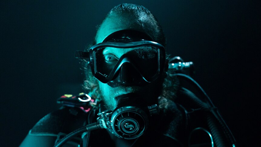 A man in a scuba diver's outfit with a green-blue filter