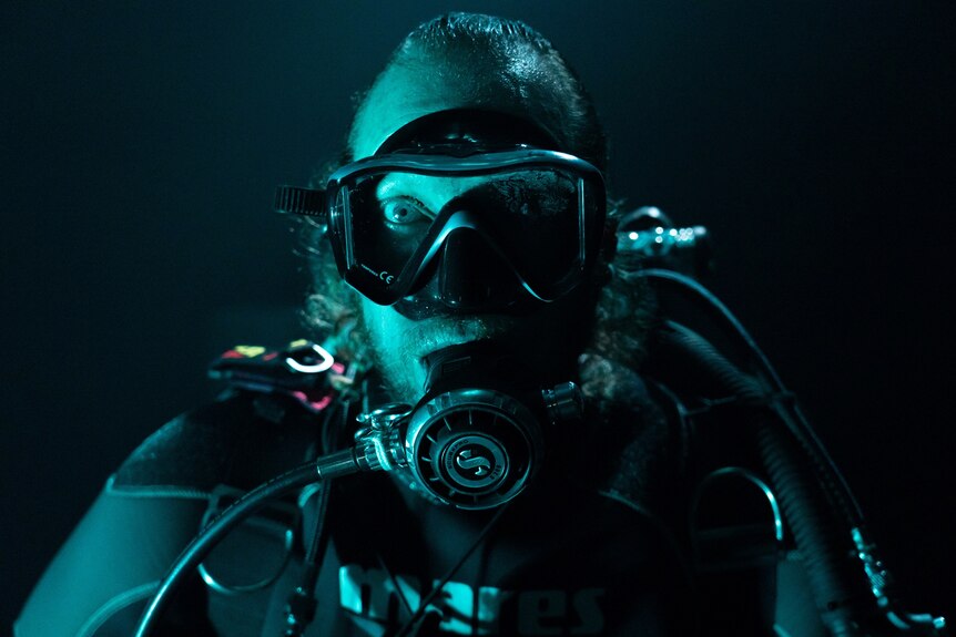 A man in a scuba diver's outfit with a green-blue filter