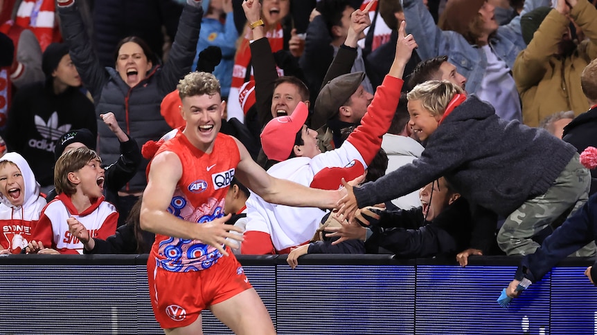 Chad Warner high-fives a member of the crowd as fans go crazy behind him