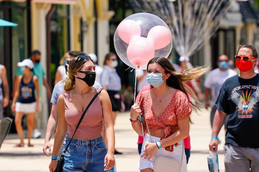 Two women in face masks walk through Florida's Disney World
