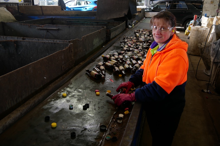 A woman sorts through material at a recycling plant.