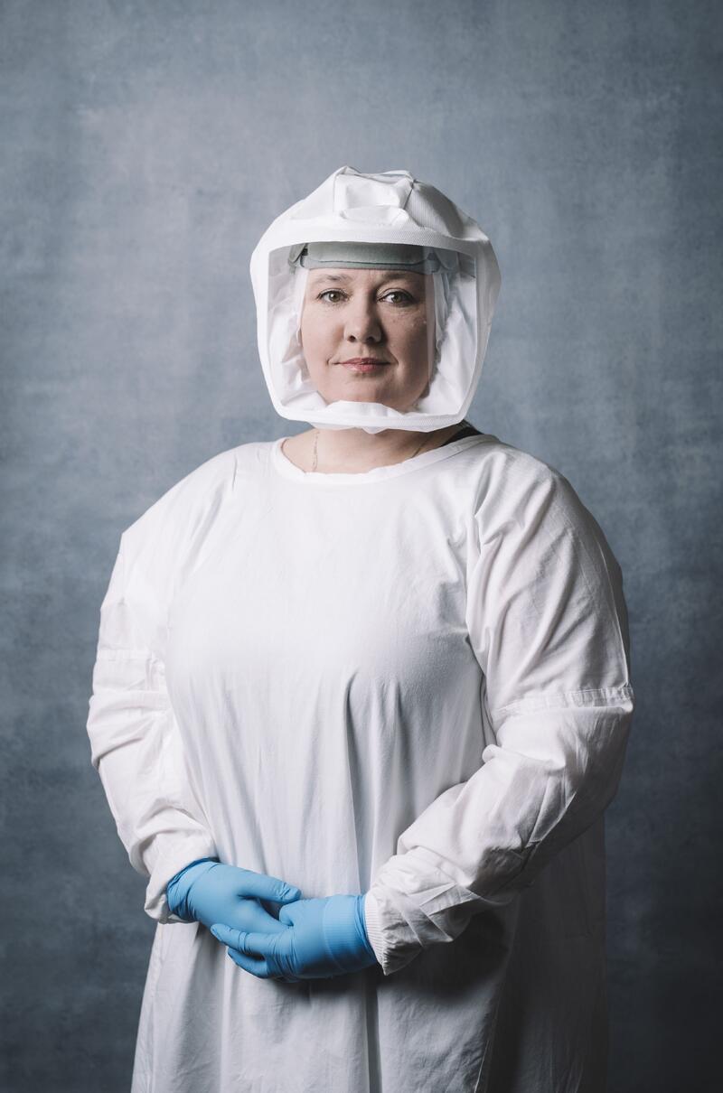 woman is standing in a protected laboratory suit looking at the camera