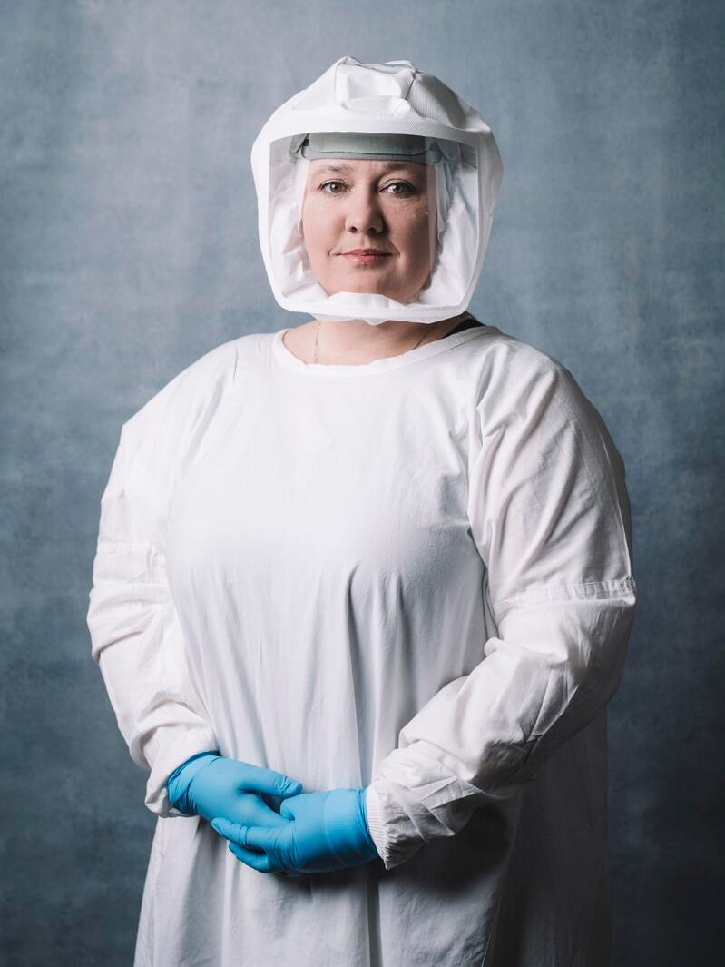 woman is standing in a protected laboratory suit looking at the camera
