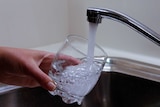 Man filling glass with water from tap