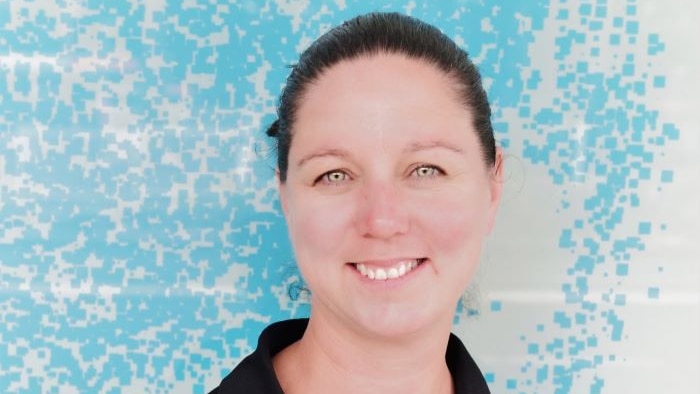 Smiling woman in front of blue speckled background.