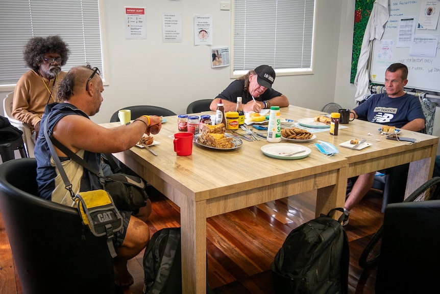 four men gather around table at homelessness hub