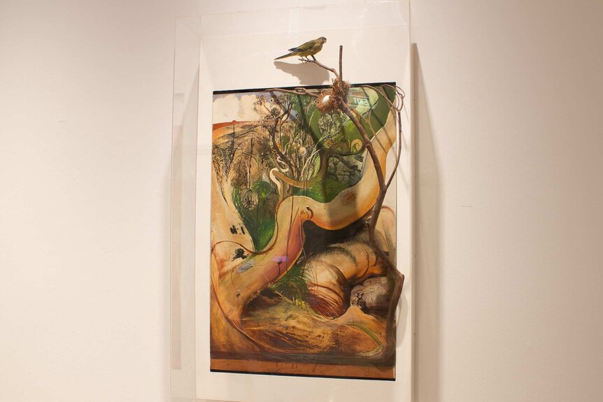 A pen, ink, collage and paint work featuring a curvy tree branch, a real branch, stuffed bird, egg and nest