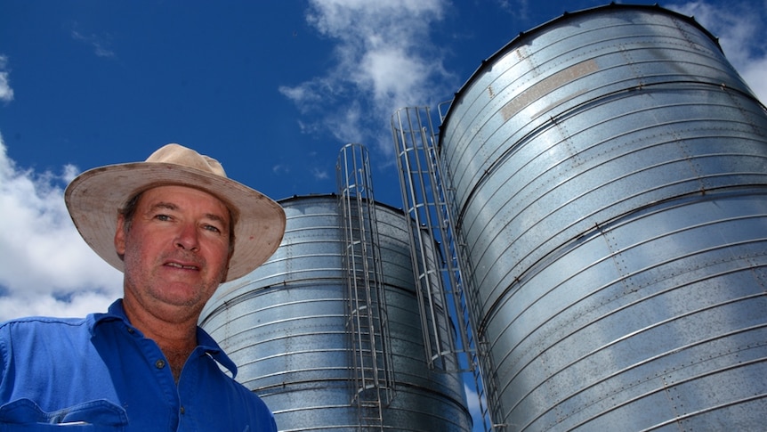 Grain grower Peter Anderson standing in front of grain silos.