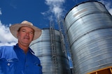 Grain grower Peter Anderson standing in front of grain silos.