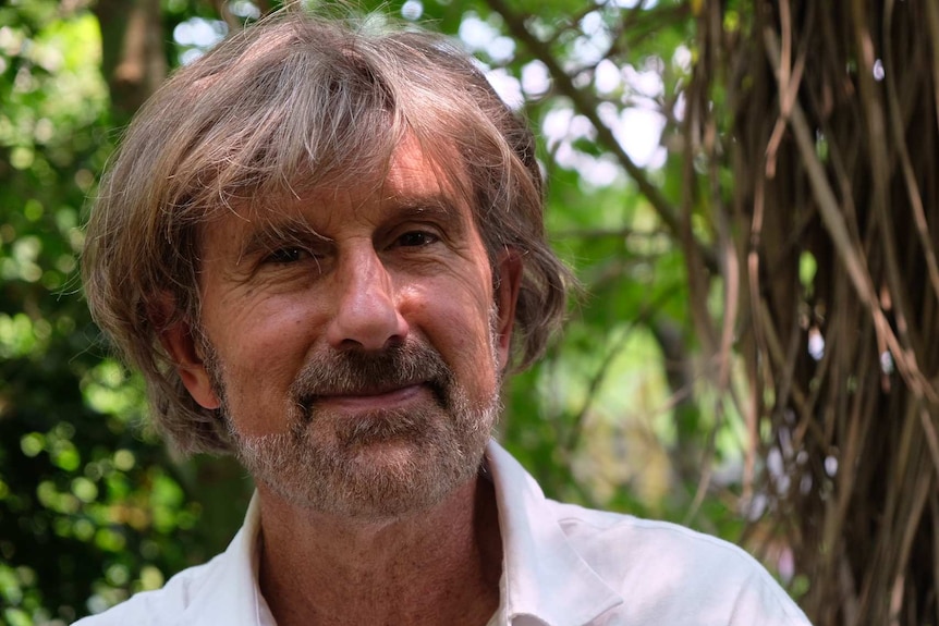 Bruno Torfs looks into the camera with greenery behind him.