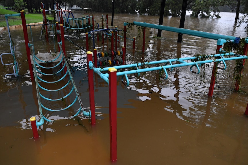 A children's playground is semi-submerged by brown floodwaters.
