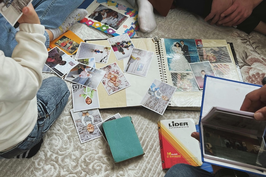 People sitting and looking at printed colour photographs in album and photo wallets