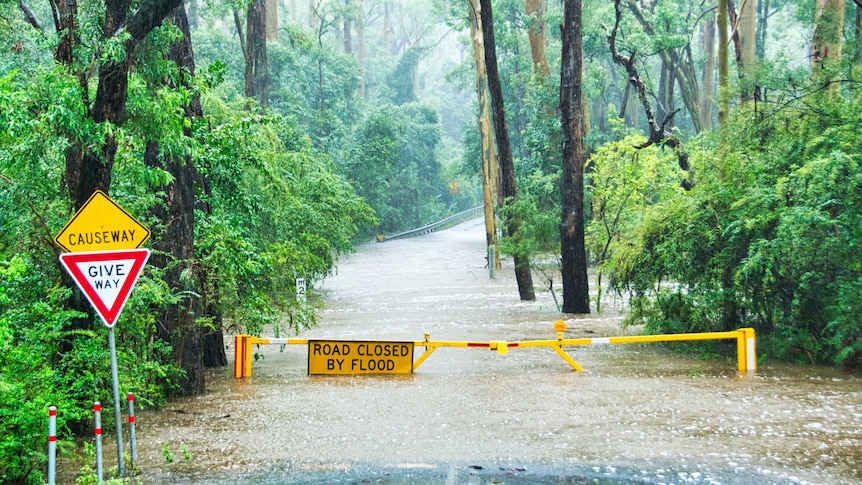 A road covered by floodwater and closed off to thoroughfare with warning signs in Annangrove, NSW in 2020