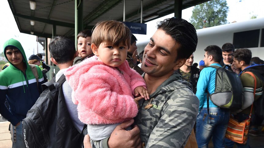 A man holds a child as they get out of a train