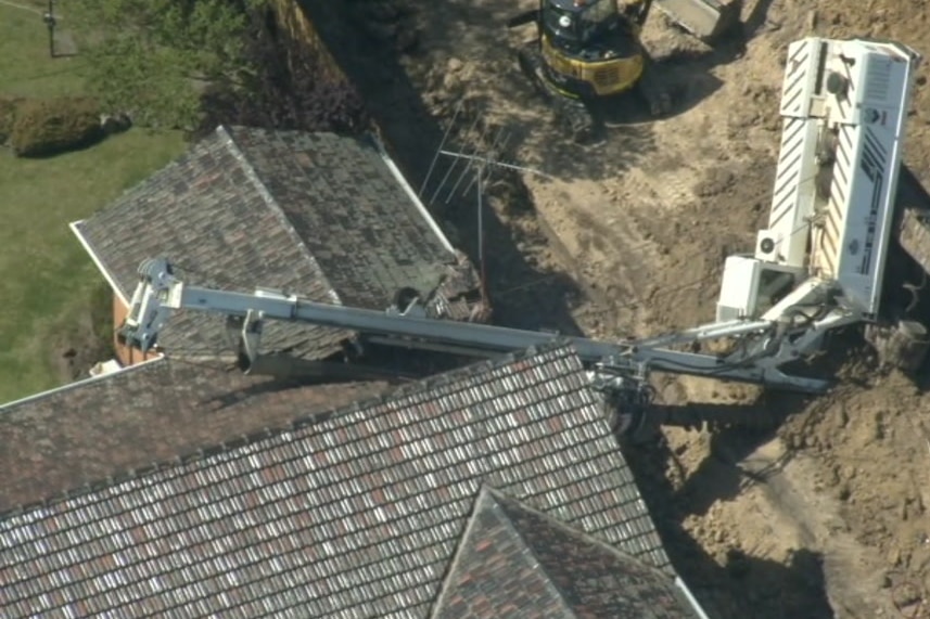 A large crane boom resting on the roof of a house.
