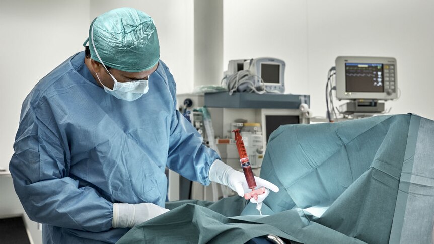 A surgeon performs a bone marrow extraction.