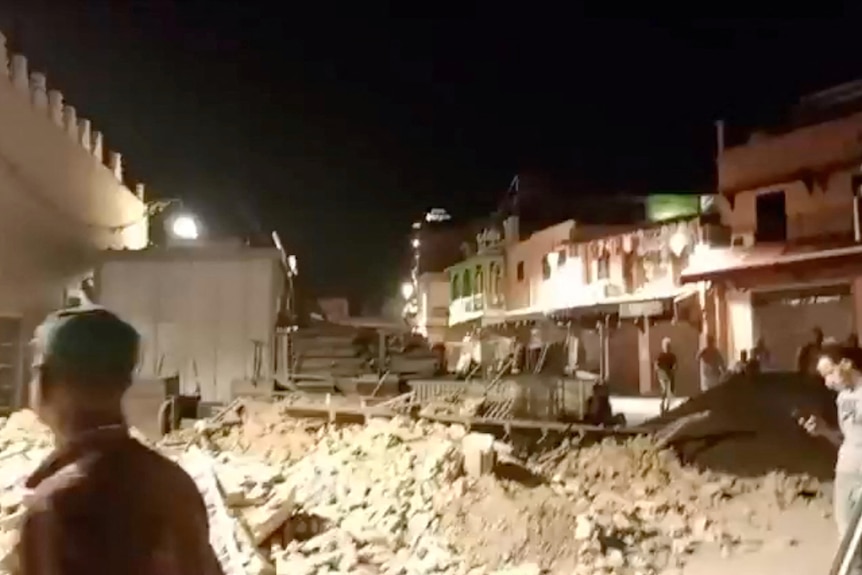 People standing around debris at night time. 