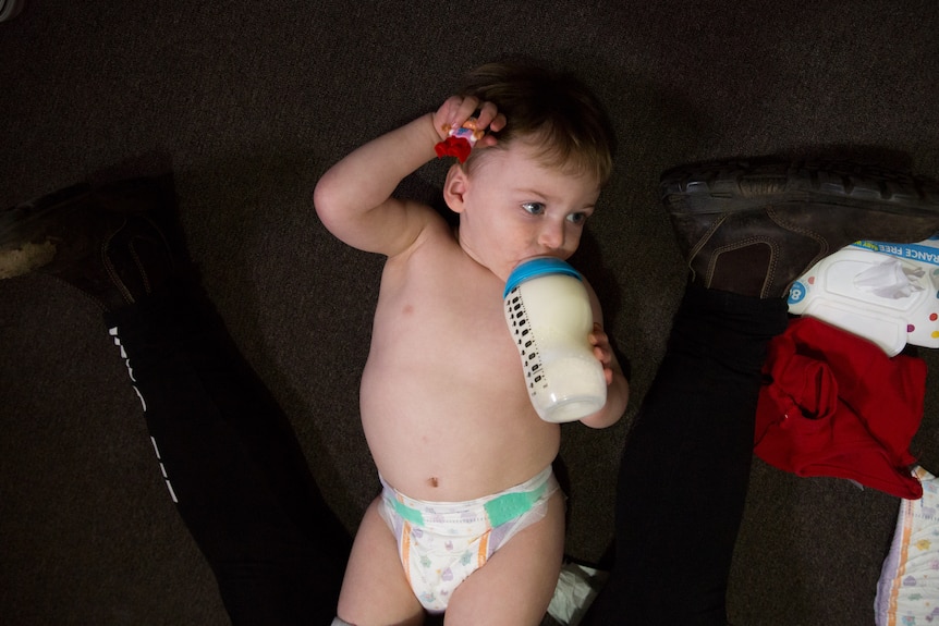 Roman lies on the floor drinking a bottle.