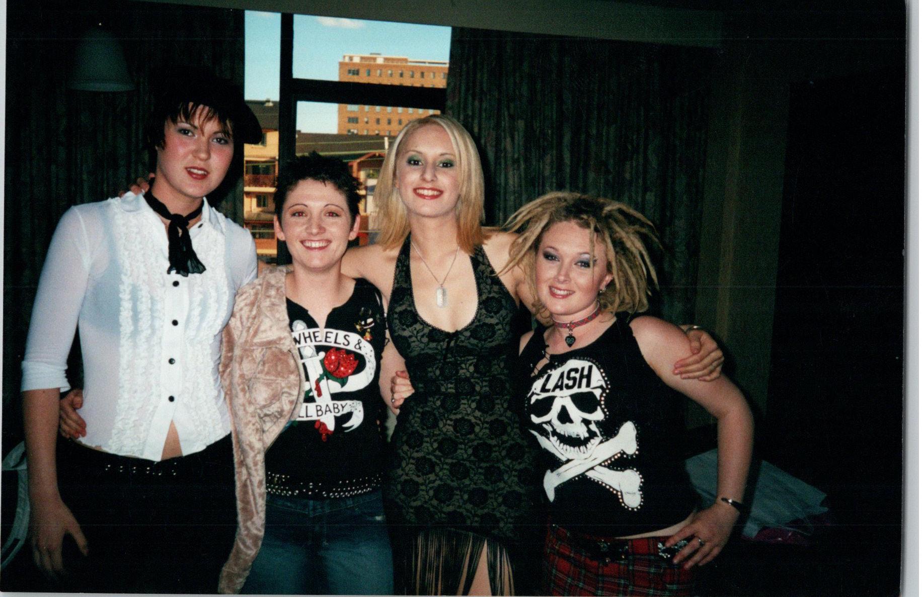 Four young women dressed as rock chics smiling at the camera