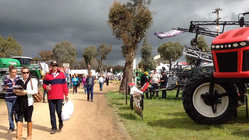 People walk next to farm equipment in a regional area of Australia