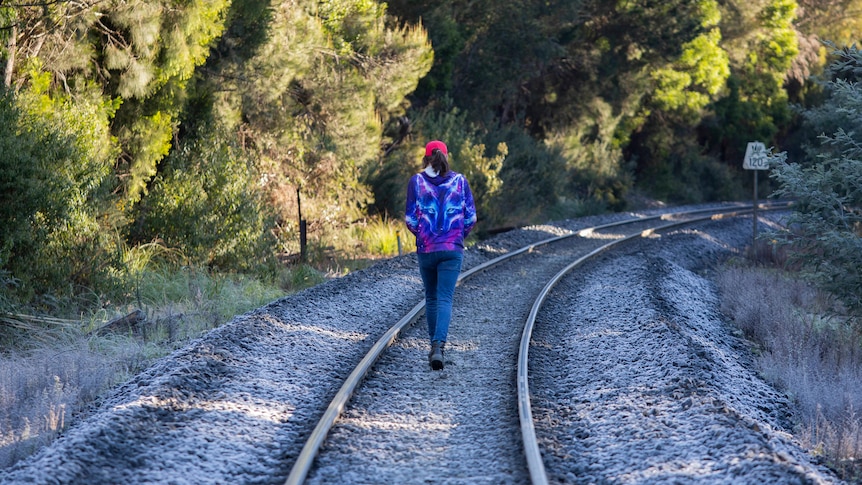 Jacob Foster walks on a set of train tracks.