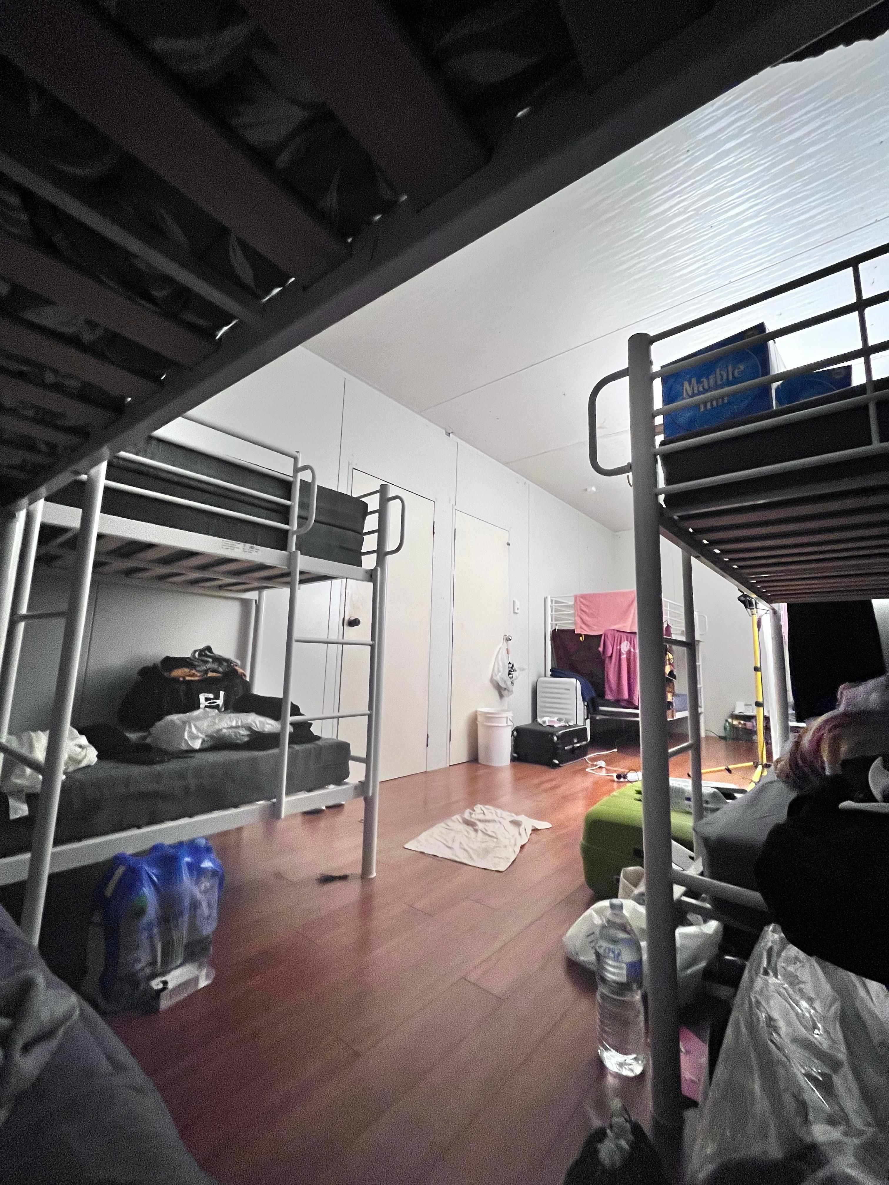 Multiple bunk beds with belongings, such as clothes scattered around a bedroom.