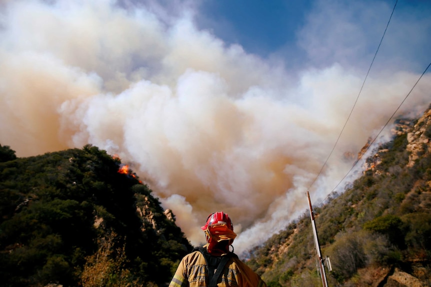 A firefighter watches a fire on a mountain in California