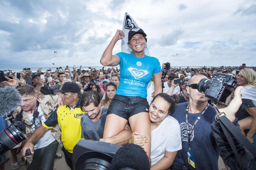 Steph Gilmore is carried up the beach on her freinds shoulders after winning a surfing competition