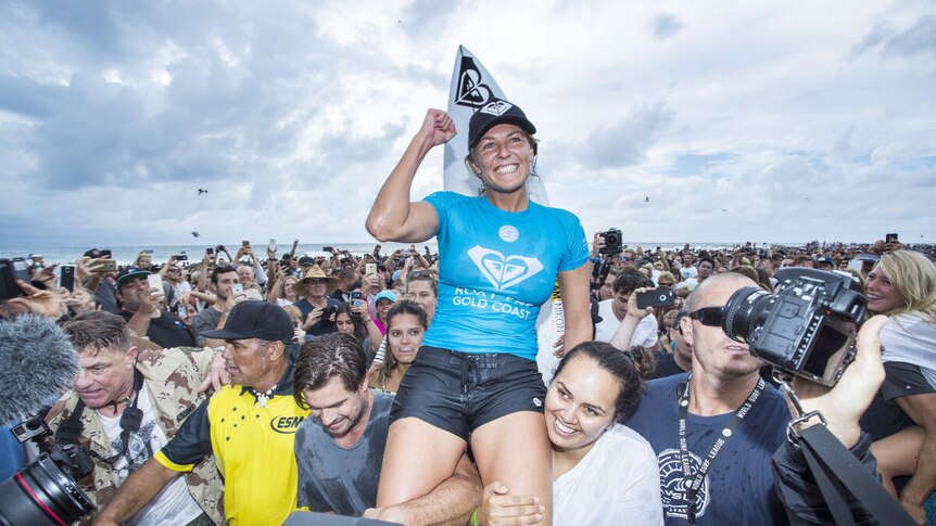Steph Gilmore is carried up the beach on her freinds shoulders after winning a surfing competition