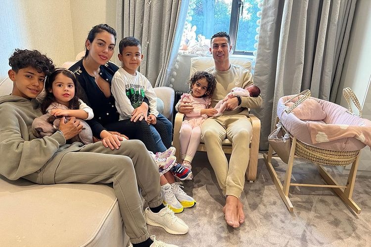 Georgina Rodriguez and Cristiano Ronaldo sitting on couches with their four children and newborn daughter