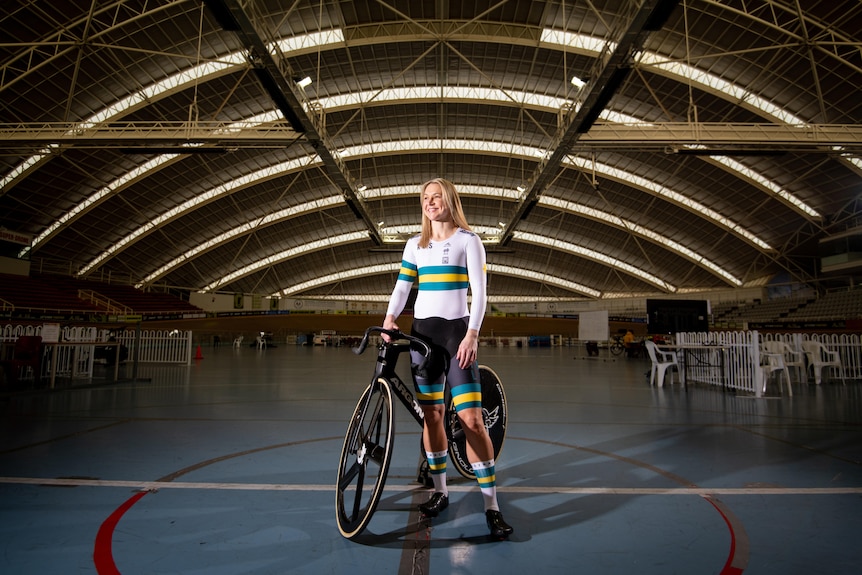 A woman with her bicycle inside a sport stadium